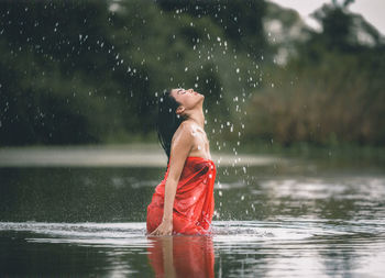 Midsection of woman splashing water in lake