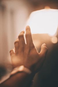 Close-up of hand by illuminated light