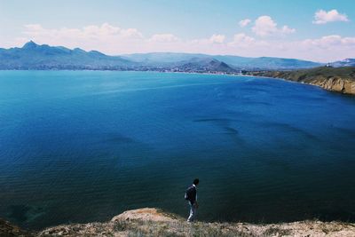 High angle view of man standing on cliff by sea