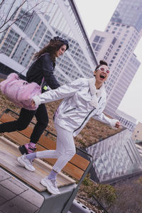 Friends walking on bench against buildings in city