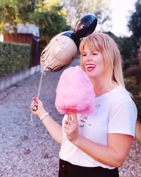 Portrait of happy girl holding pink while standing outdoors