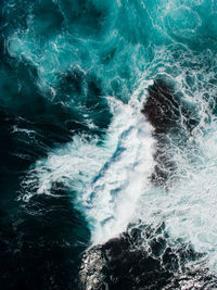 High angle view of waves splashing on rocks