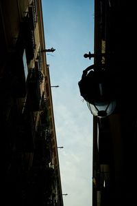 Low angle view of street light by building against sky