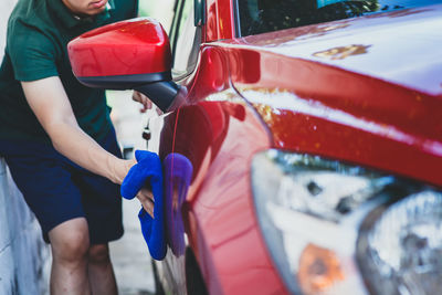 Midsection of man cleaning car outdoors