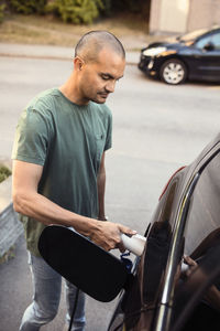 Man charging electric car on roadside