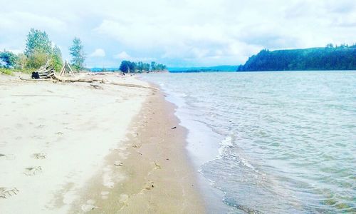 Scenic view of beach against cloudy sky