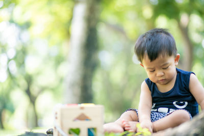 Boy looking away while sitting outdoors