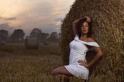 Young woman with hand raised on field against sky