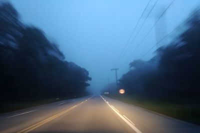 Cars on road against sky at dusk