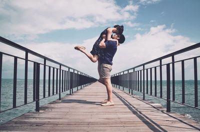 Full length of woman standing on footbridge against sky
