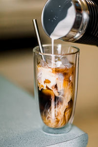 Close-up of coffee pouring in glass on table