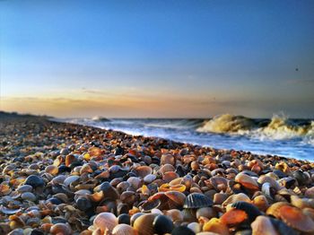 Rocks on beach against sky during sunset