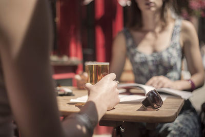 Midsection of woman drinking glass on table at restaurant