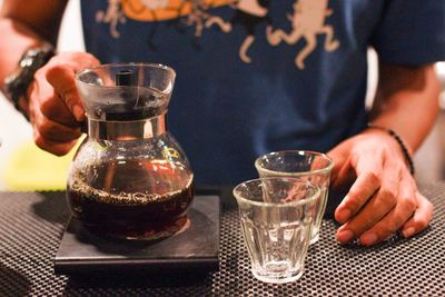 Midsection of woman holding drink on table