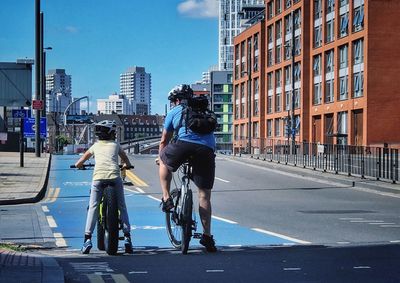 Rear view of people riding bicycle on road