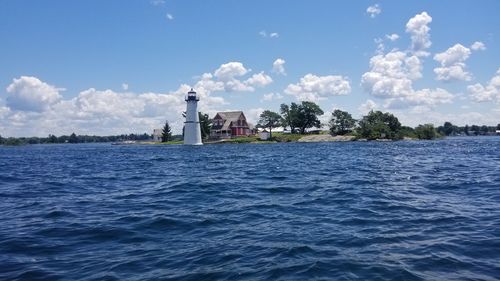 Lighthouse by sea against sky