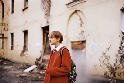 Thoughtful woman standing against old building