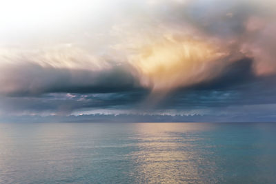 Scenic view of sea against dramatic sky during sunset