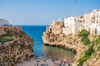 Buildings by sea against clear blue sky