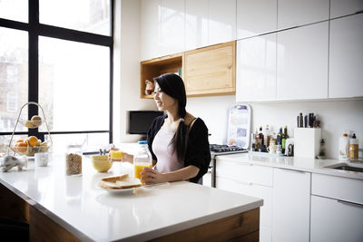 Happy woman drinking juice in kitchen