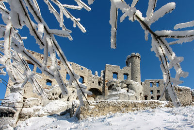 Low angle view of snow covered field against clear blue sky