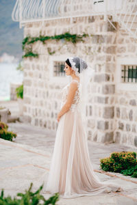 Side view of woman standing against building