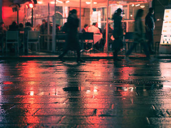 Reflection of people in illuminated city during rainy season