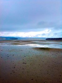 Scenic view of beach against cloudy sky