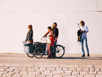 People with bicycle standing against wall