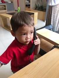 Cute boy talking on mobile phone at home