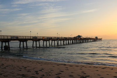 Pier over sea against sky during sunset