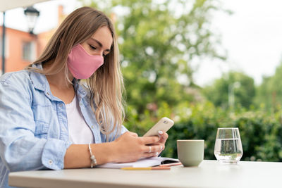 Businesswoman wearing protective face mask working in outdoor cafe