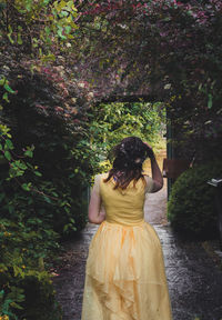 Rear view of woman standing by flowering plants