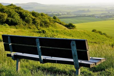 Empty bench on grassy landscape