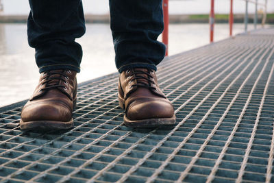 Low section of man standing on metal pier