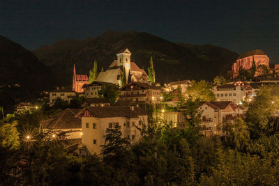 Town by mountains against sky at night