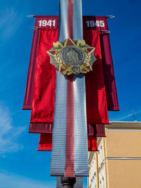 Low angle view of red flags against blue sky