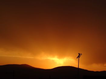 Low angle view of silhouette mountain against orange sky