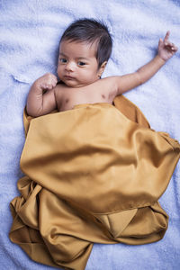 High angle view of cute baby lying on bed