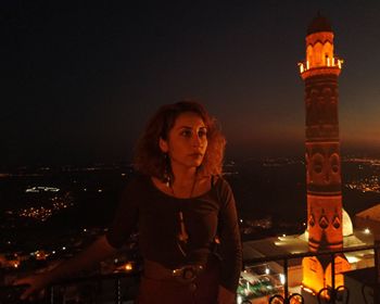 Portrait of young woman standing in city at night