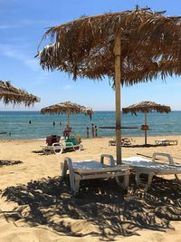 Deck chairs and parasols on beach against sky