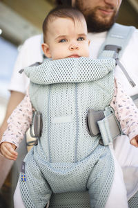 Midsection of father carrying baby girl while standing outdoors