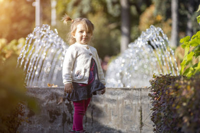 Charming toddler in the park with fountains in the background