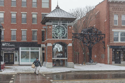 Woman walking by building in city during winter