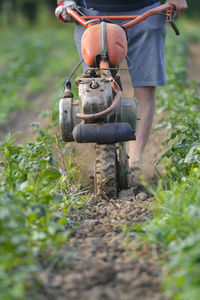 Low section of man with motocultivator on field