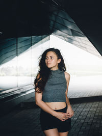 Beautiful woman standing on walkway against building