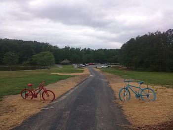 Cars parked on road against cloudy sky