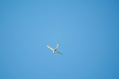 Low angle view of airplane against clear blue sky