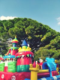 Multi colored toys against trees and plants against sky