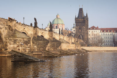 Low angle view of charles bridge and cathedral by river in city against clear sky